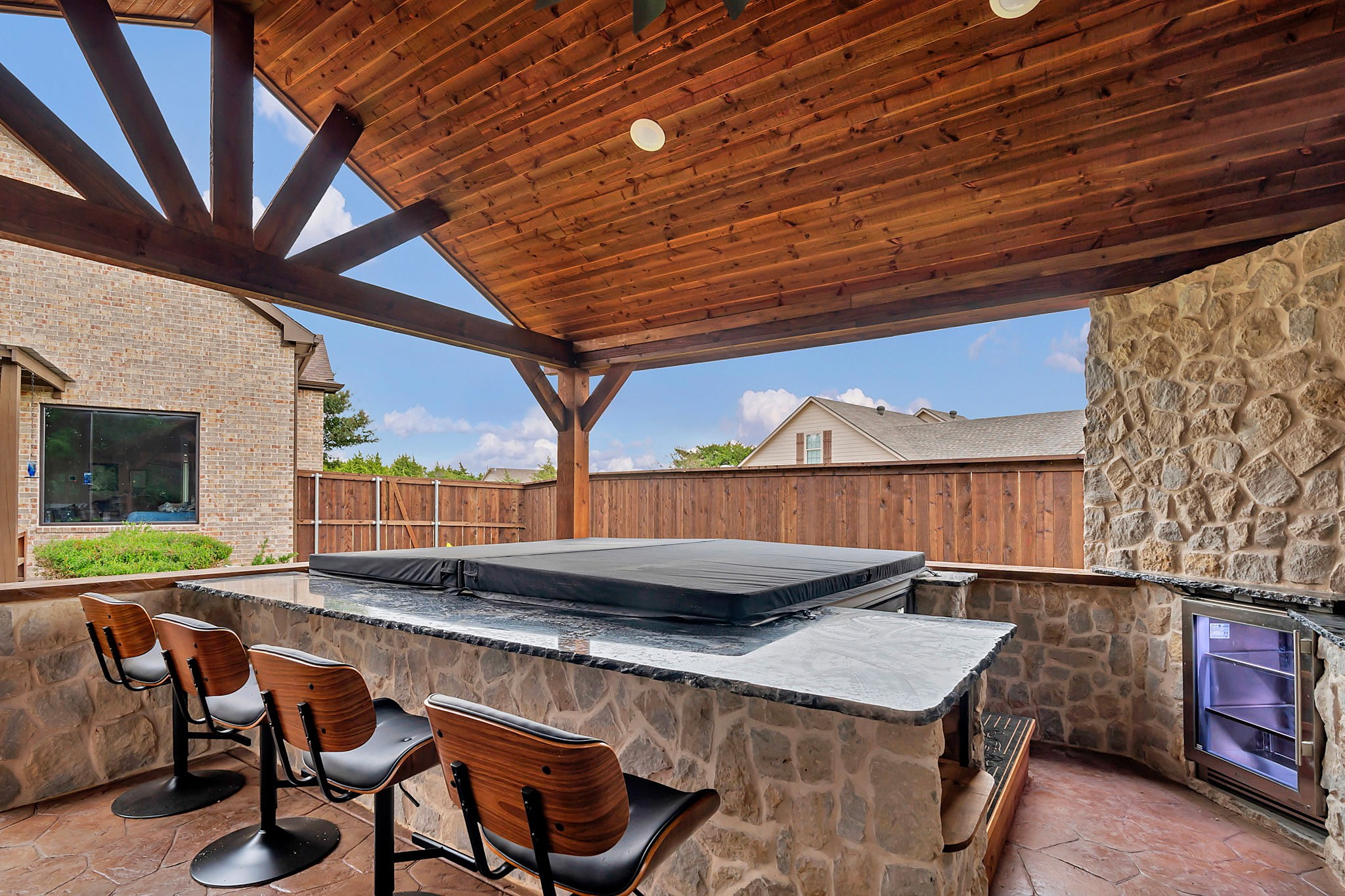 Spa built into a stone bar under a cedar pergola